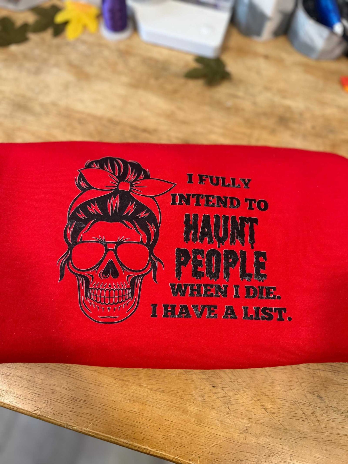 Eerie "I intend to Haunt People" Halloween t-shirt with skull design on red fabric.