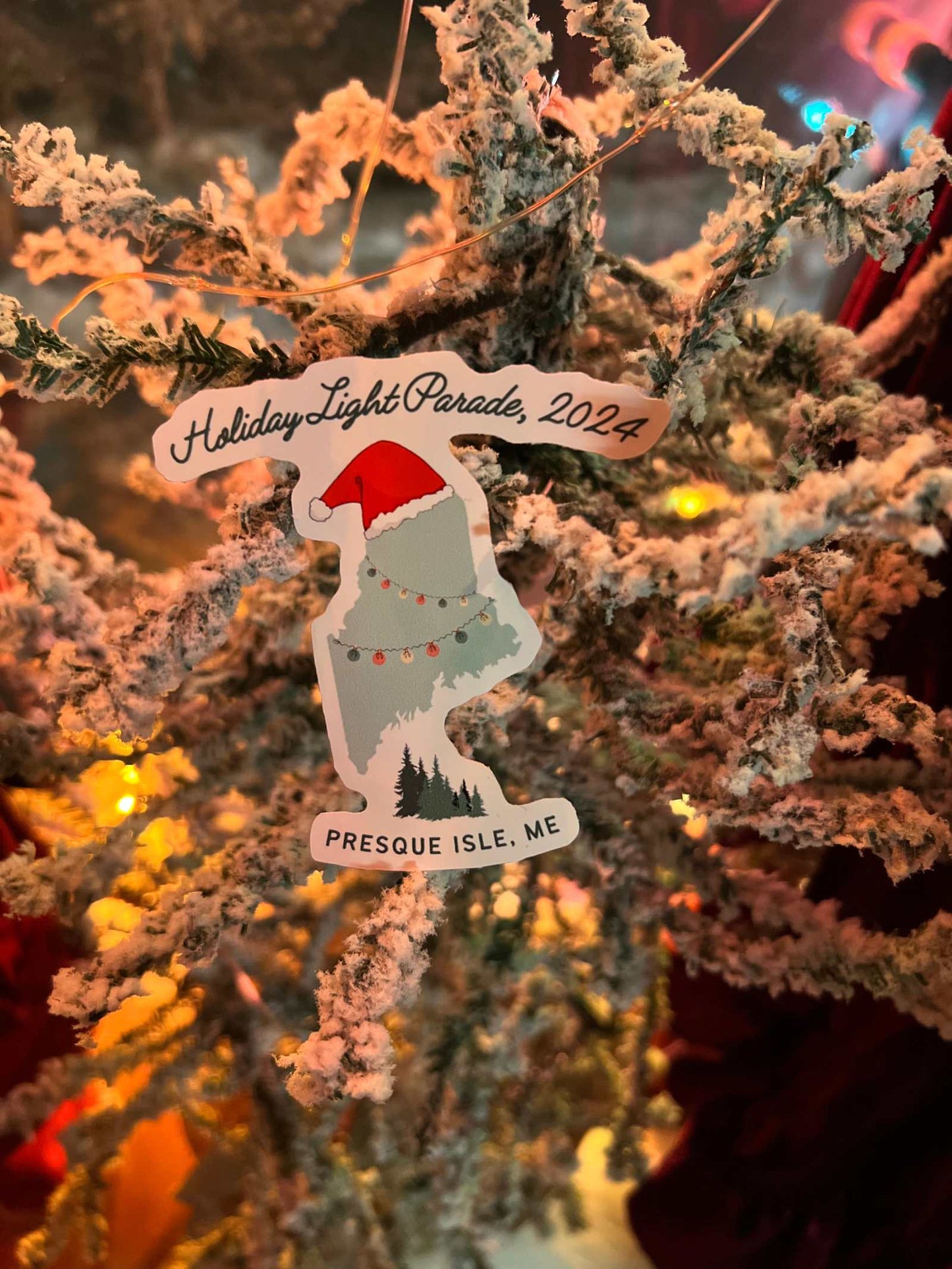 Stickers featuring Presque Isle, ME Holiday Light Parade 2024 design on holiday-decorated background.
